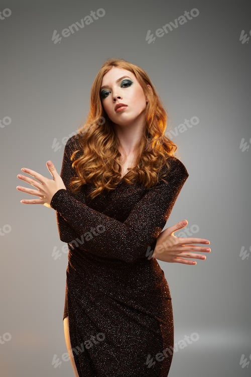 Preview: Stylish redhead woman poses confidently in a grey studio setting
