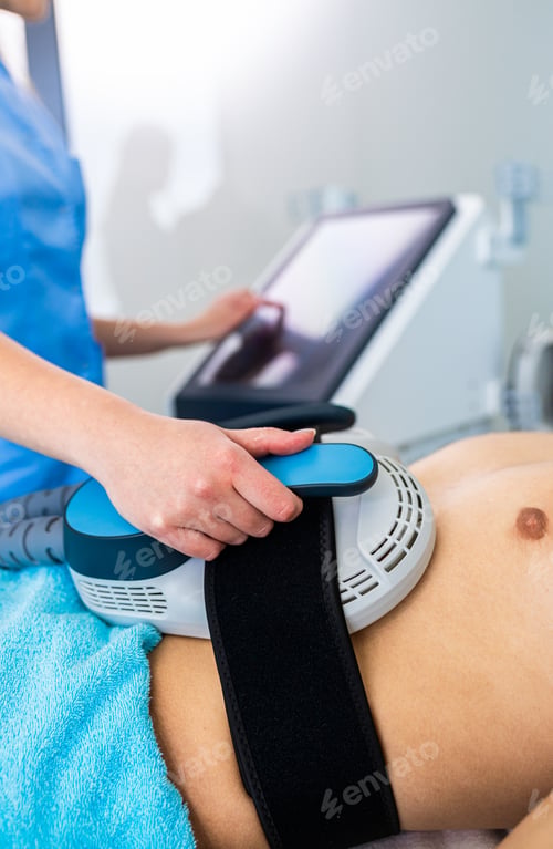Preview: Beautician therapist applying burn fat and build muscles treatment in beauty salon to young man.