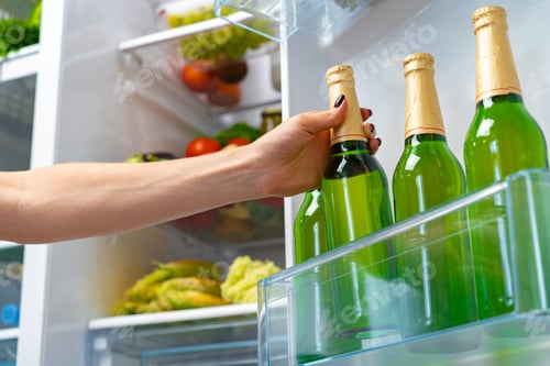 Preview: Female hand taking bottle of beer from a fridge
