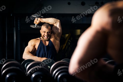 Man Lifting Dumbbell in Dark Gym Setting