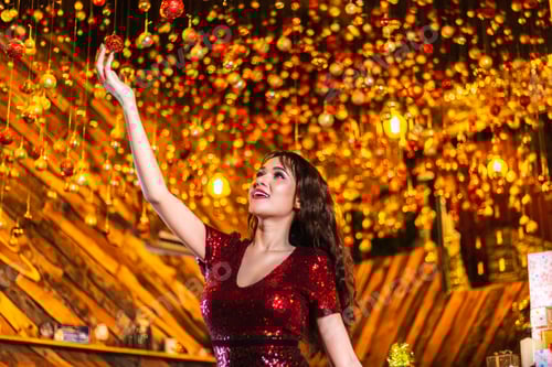 Preview: woman decorating colored balls and glowing lights for Christmas Day.
