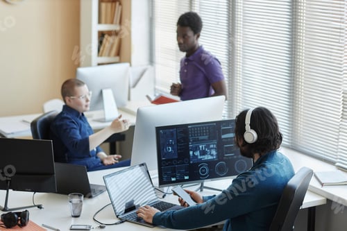 Vista previa: Joven trabajador de un centro de ciberseguridad sentado frente a las computadoras