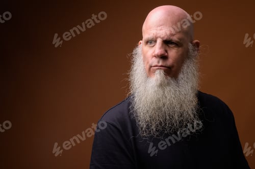 Preview: Mature bald man with long gray beard against brown background