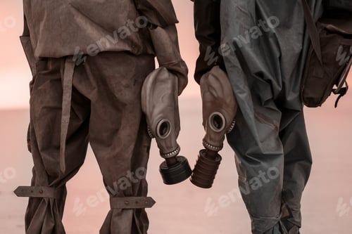 Preview: Two people with gas masks and chemical protection suits on the background of the scorched dead earth