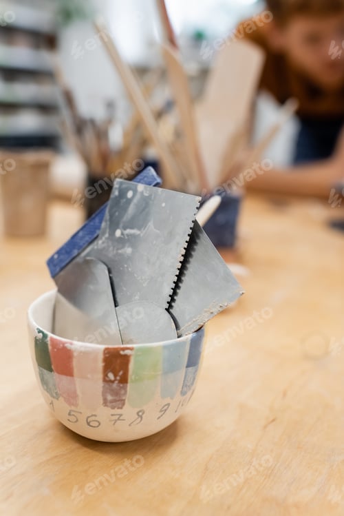 Preview: Metallic pottery steel scrapers on table in workshop