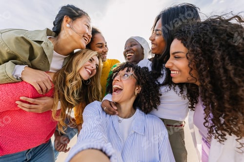 Preview: Diverse group of happy female friends laughing together outdoors.