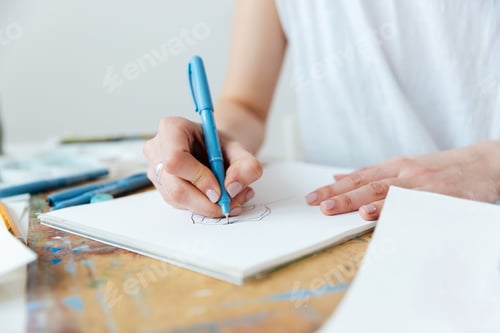 Preview: Woman artist making sketches by gel ink pen at table