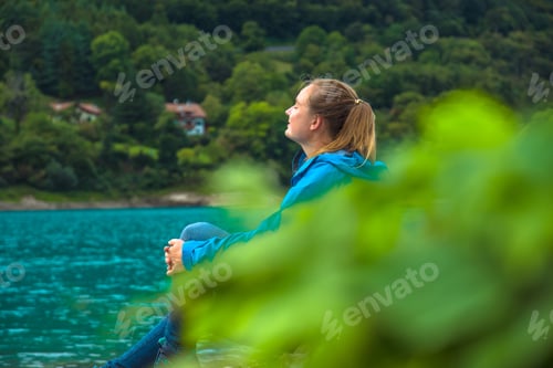 Preview: Female in blue jacket is resting from a hike outdoors