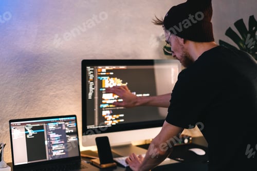 Preview: Young man mobile developer writes program code on a computer, programmer work in home office.