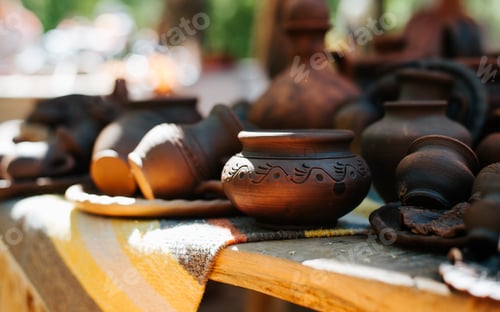 Preview: Medieval pottery, close-up of decorated clay cups and plates on a table outdoors. Selective focus