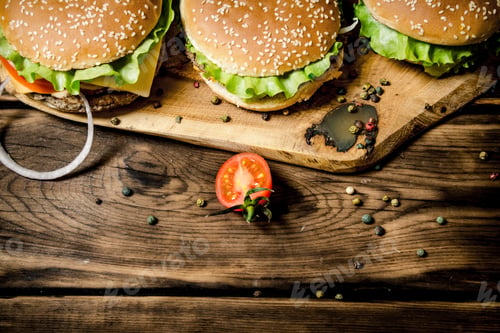 Preview: Three finished Burger with meat and vegetables on wooden stand.