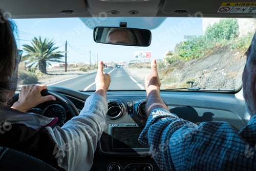 Preview: couple of two seniors together in a car doing the yes sign with their hands
