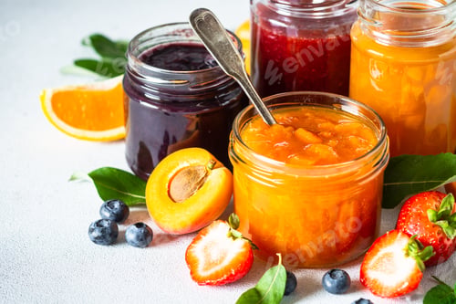 Preview: Homemade jam in glass jars at white table.