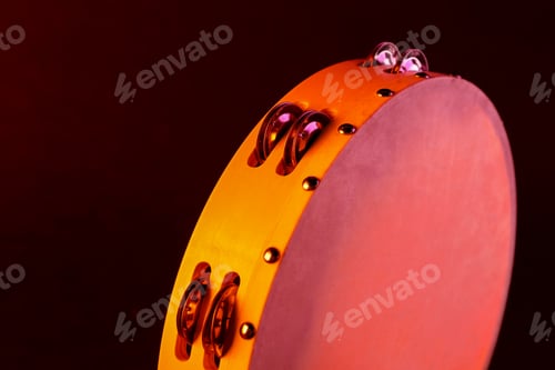 Preview: Tambourine in color light on black background, closeup. Space for text