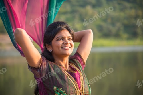 Preview: Young happy Indian girl playing with her pink scarf at outdoor.