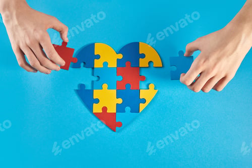 Preview: Autistic boy hands holding jigsaw puzzle heart shape. World Autism Awareness Day