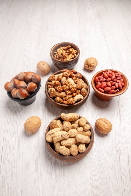 Preview: side view from afar nuts on the table walnuts peanuts hazelnuts in five brown bowls in the center of