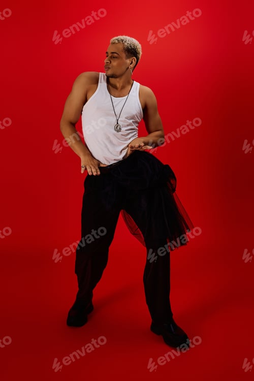 Preview: Young man showcases bold style in striking red studio with fashionable attire
