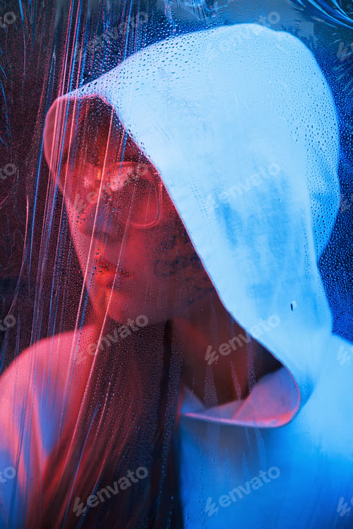 Preview: Water on the material. Studio shot in dark studio with neon light. Portrait of young girl