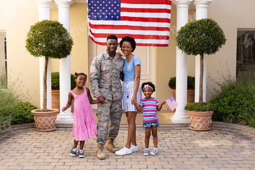Preview: Full length portrait of happy african american family with military man against usa flag at entrance