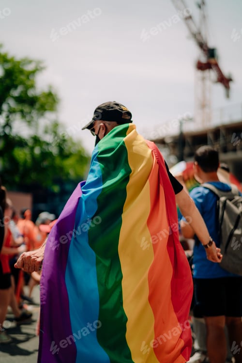 Preview: Vertical closeup of the man wearing a rainbow flag as a cape.