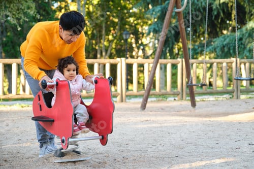 Preview: Ecuadorian father playing with toddler daughter in a playground.