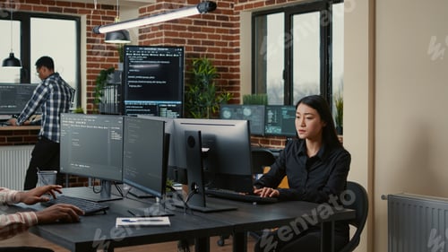 Preview: Programer with clipboard sitting down at desk in front of programer writing code