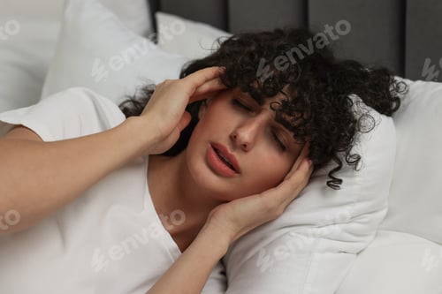Preview: Young woman suffering from headache in bed at night