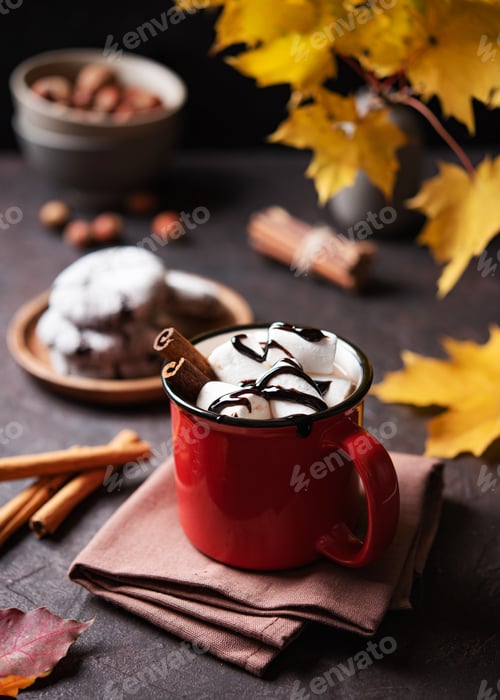 Preview: Red cup of aroma hot chocolate with marshmallows on a brown background with autumn maple leaves