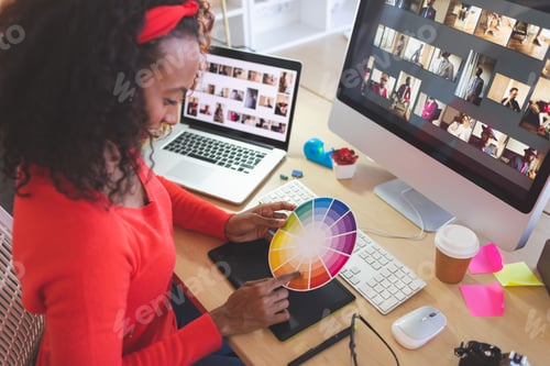 Preview: Female graphic designer using color swatch at desk in a modern office