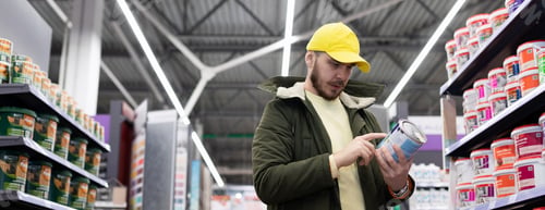 Preview: a buyer among the racks in a construction hypermarket with a phone in his hands