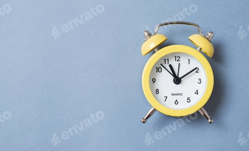 Preview: One small alarm clock with a double bell made of yellow metal on a blue background. Top view