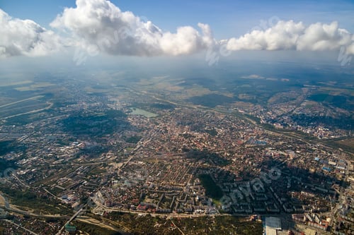 Preview: Aerial view from airplane window at high altitude of distant city covered with white puffy cumulus