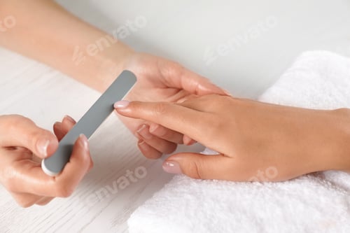 Preview: Manicurist filing client's nails at table, closeup. Spa treatment