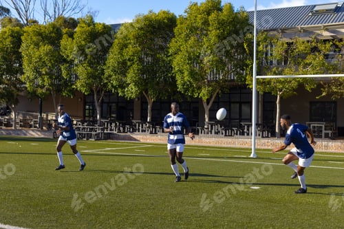 Preview: Three African American young male athletes training with a rugby ball on a field outdoors