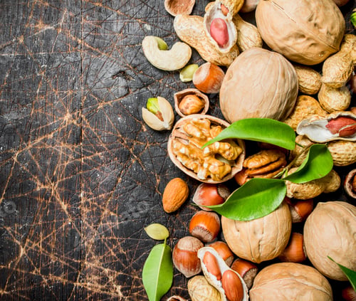 Preview: Nuts background. Different kind of nuts with green leaves.