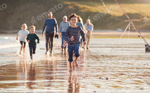 Preview: Children Run Ahead As Multi-Generation Family Walk Along Shore On Winter Beach Vacation