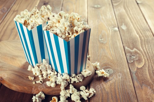 Preview: Popcorn boxes filled with popcorn on a wooden table with scattered popcorn around