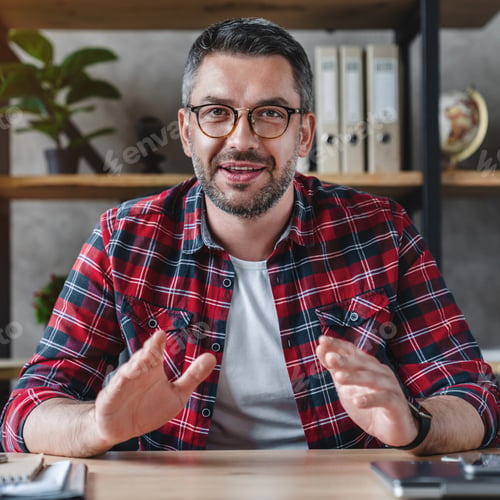 Man in Plaid Shirt Seated at Desk