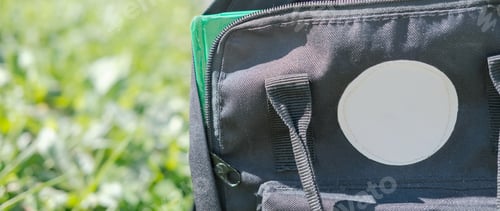 Preview: black school bag on a grass. back to school concept.