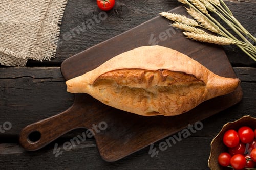 Preview: Fresh bread on a board with wheat on a wooden background