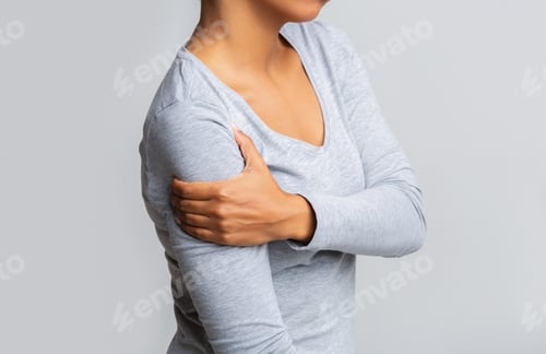 Preview: Afro woman holding her forearm over grey background