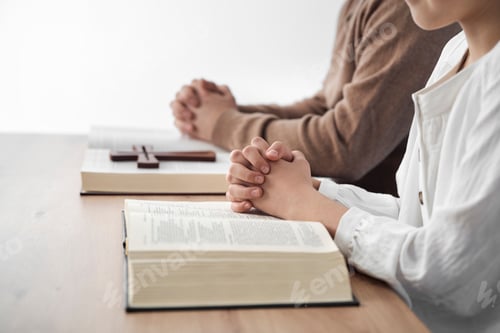 Preview: Father and daughter siting by desk and reading a holy bible