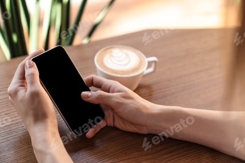 Preview: Cropped photo of caucasian woman using cellphone and drinking coffee