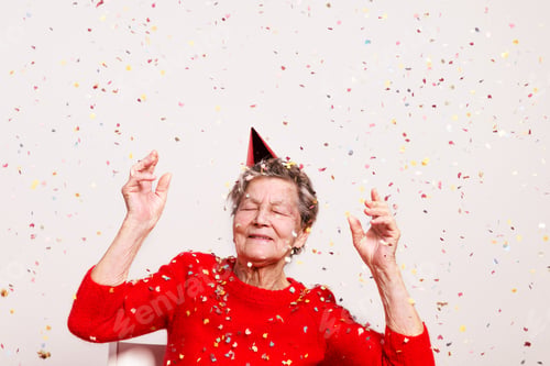 Preview: Portrait of a senior woman in studio on a gray background. Party concept.