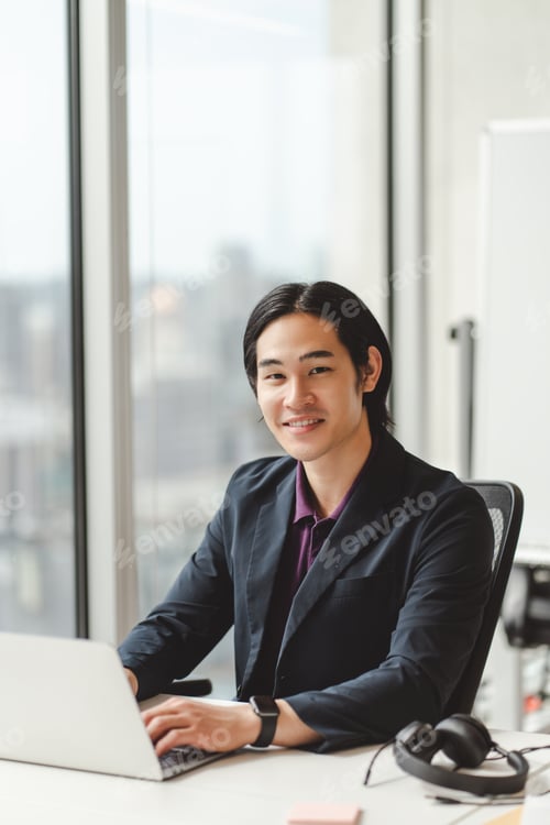 Preview: Smiling successful asian man using laptop confident japanese freelancer working from home