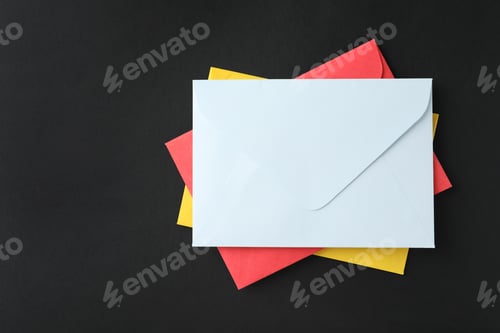 Preview: Stack of colorful paper envelopes on black background, top view