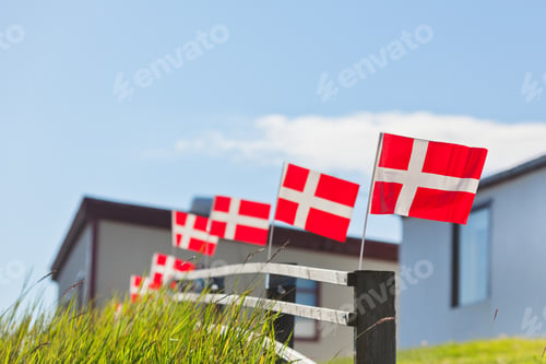 Preview: Danish flags in a row on a wooden fence in a village