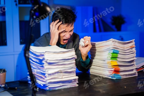 Preview: An Asian businessman works late at night in the office,dealing stress,migraine headaches,overtime