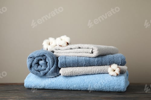 Preview: Folded towels and cotton on wooden table against grey background, space for text